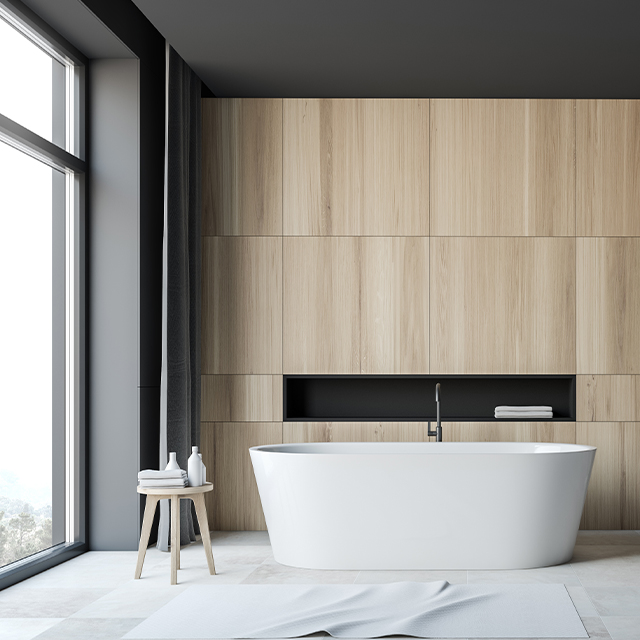 Modernes Badezimmer mit einer freistehenden weißen Badewanne vor einer Wand mit Holzeinbauschränken