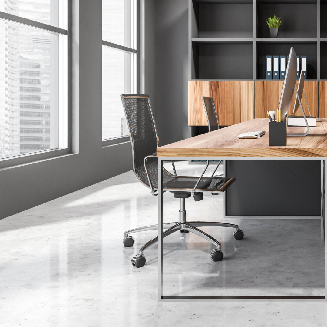 Heller Büroraum mit einem großen Schreibtisch aus Metallgestell und Holzplatte sowie einem halboffenen Einbauschrank