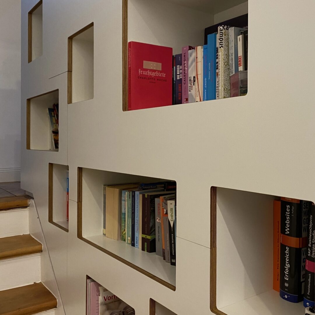 Weißes Einbauregal mit abgerundeten offenen Fächern für Bücher und Co. an einer Treppe