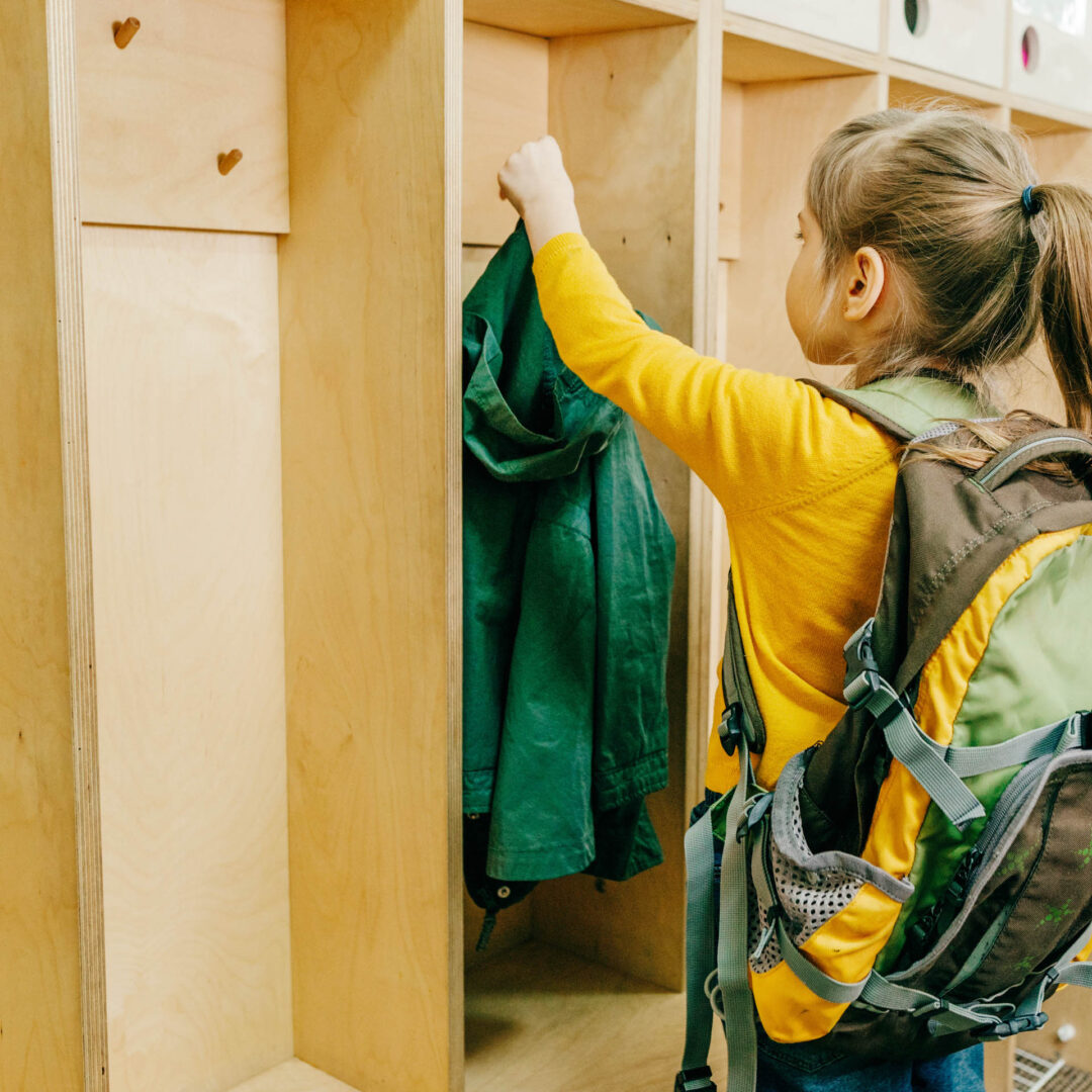Maßgefertigte Garderobe aus hellem Holz mit abgetrennten Einzelbereichen für einen Kindergarten