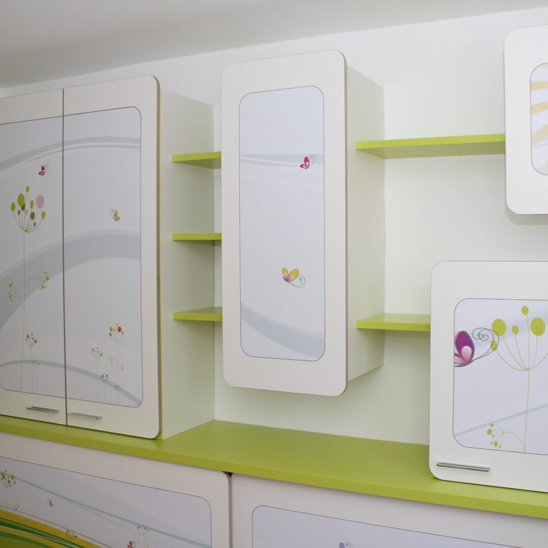 Grün-weiße Schrankwand in einem Kinderzimmer mit offenen und geschlossenen Elementen