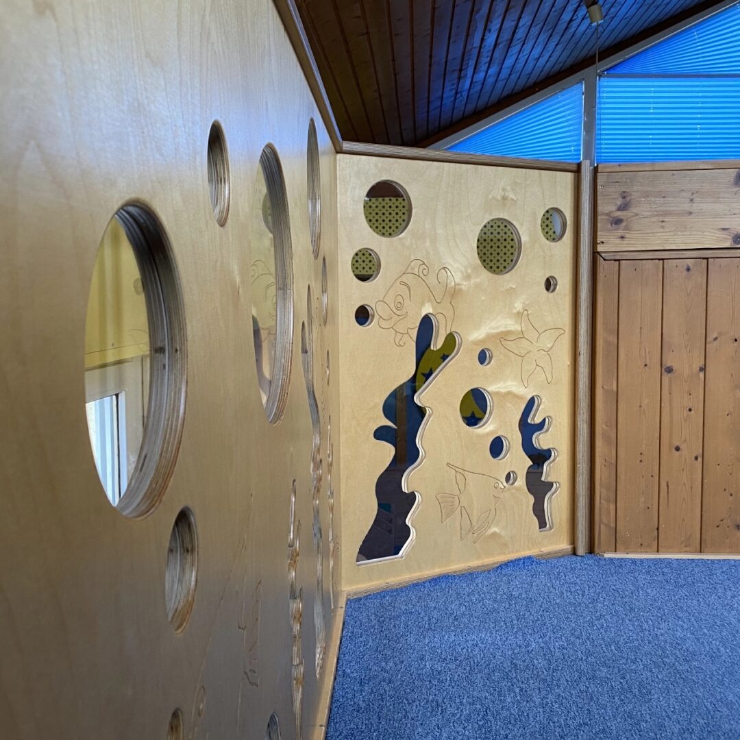 Aufnahme einer Spielwand aus Holz mit verschiedenen Gucklöchern und tierischen Motiven