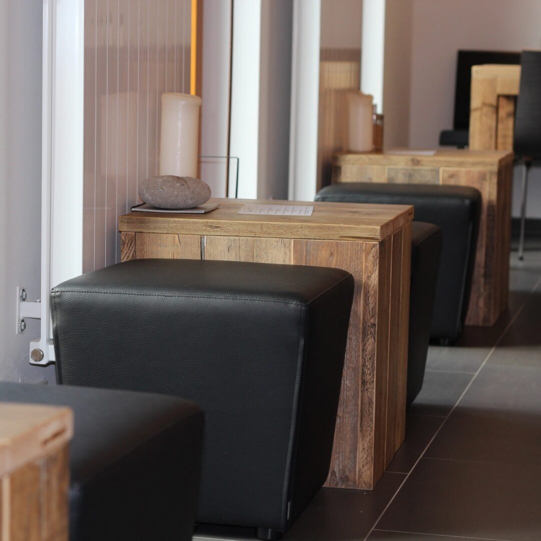 Mehrere dunkelbraune Hochtische aus massivem Holz mit schwarzen Sitzhockern in einem modernen Empfangsbereich