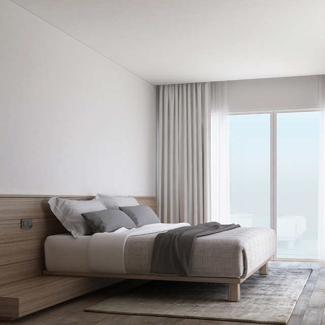 Großes Doppelbett aus Massivholz mit integrierten Nachttischen auf einem Teppich in einem hellen Schlafzimmer