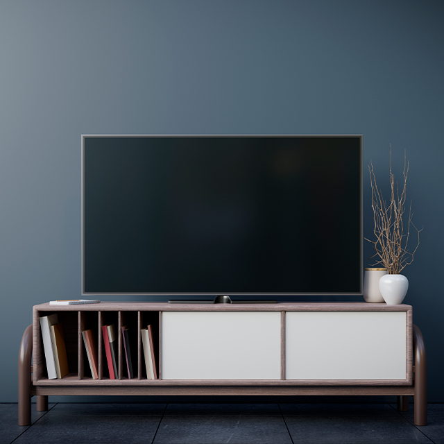 Halboffenes TV-Board auf ausgefallenen Metallfüßen vor graublauer Wand im Wohnzimmer