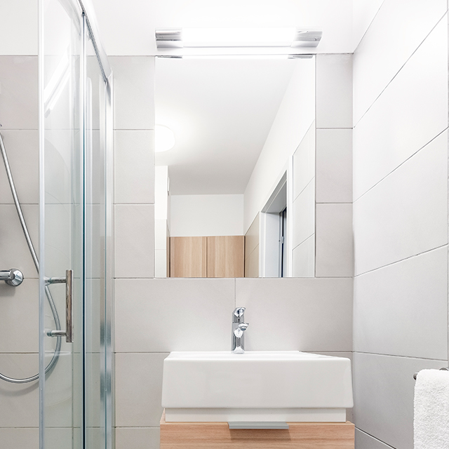 Eintüriger Spiegelschrank mit integrierter Oberbeleuchtung in einem kleinen innenliegenden Duschbadezimmer
