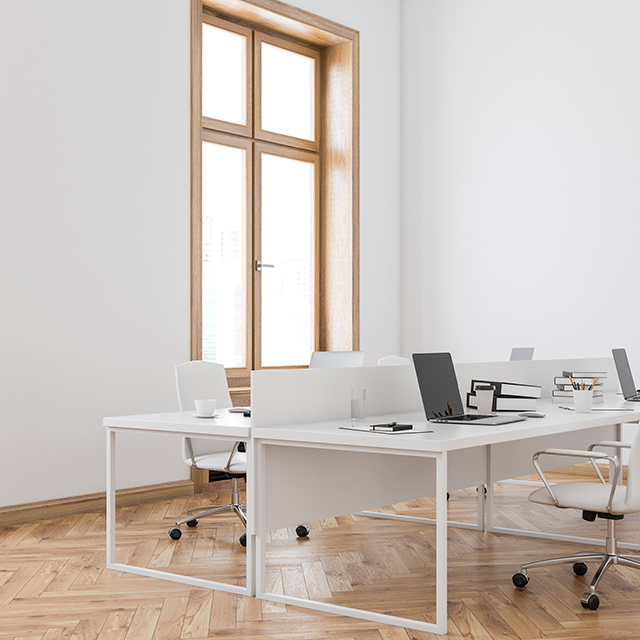 Offener Büroraum mit vier weißen Schreibtischen und hell gepolsterten Bürostühlen