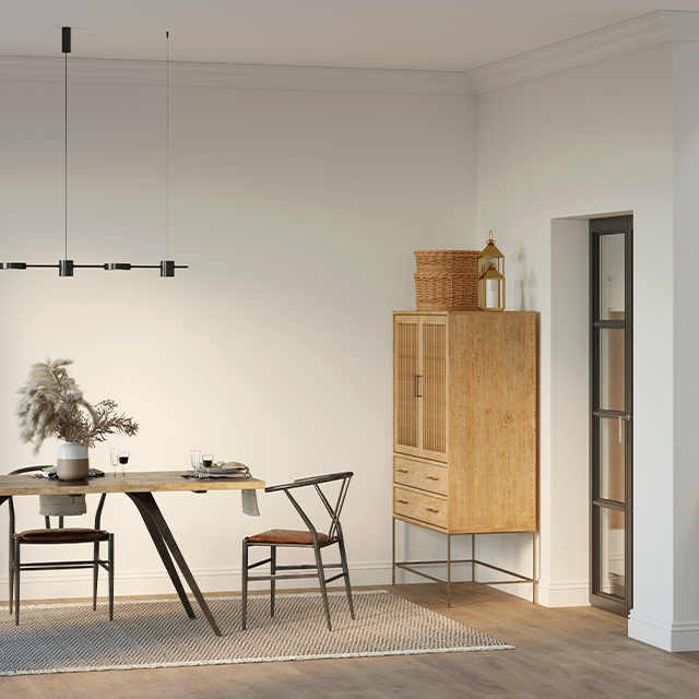 Helles Esszimmer mit einem großen Holztisch mit Metallbeinen und einem ausgefallenen Sideboard aus Holz