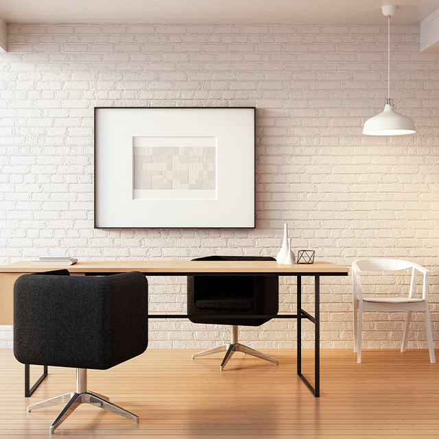 Beratungsraum mit einer weißen Backsteinwand, einem Tisch aus Holz- und Metallelementen und zwei gepolsterten Stühlen