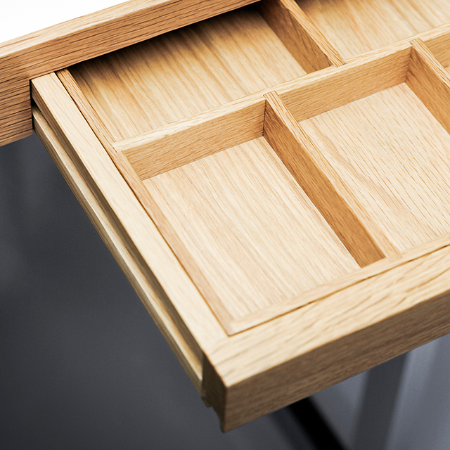Nahaufnahme einer geöffneten Schublade mit integriertem Ordnungssystem eines Holzmöbelstücks