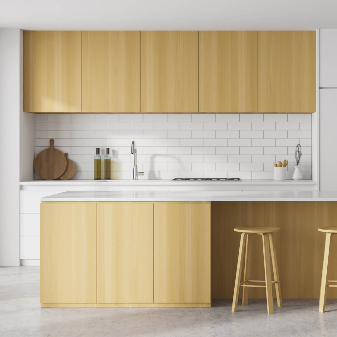 Frontansicht einer Küche aus hellem Holz mit grifflosen Schränken, weißer Arbeitsplatte und einer großen Kücheninsel mit zusätzlichen Unterschränken