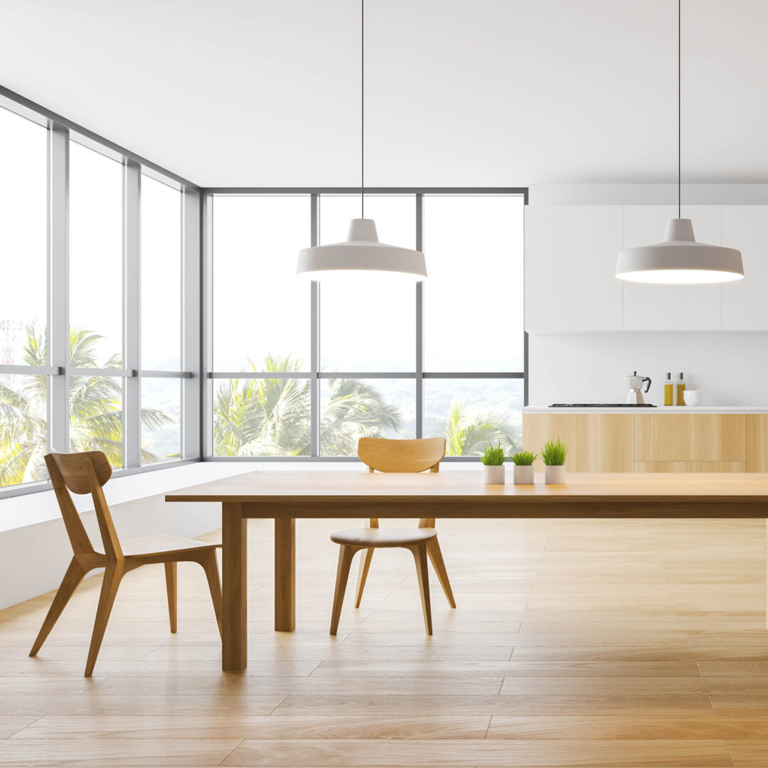 Sehr langer Esstisch aus hellem Holz in einer freundlichen, offenen Küche mit sehr großen Fenstern