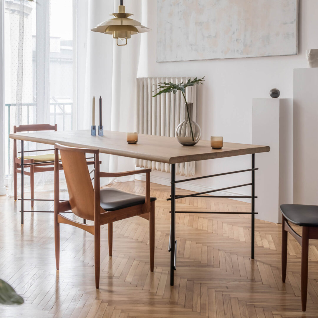 Esstisch mit ausgefallenen Metall-Tischbeinen und drei verschiedenen Designer-Stühlen in einem Altbau-Esszimmer